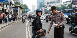 TILANG BAN GUNDUL - Foto hasil olahan Akal Imitasi (AI) Gemini menampilkan seorang pengendara ditilang polisi karena mengendarai motor dengan ban dalam keadaan gundul. Jagad maya dihebohkan berita viral gan gundul bisa kena tilang polisi dengan denda Rp 250 ribu atau ancaman kurungan penjara 1 bulan. Benarkah? Ini faktanya, Kamis (30/1/20526). GEMINI AI/REPRO
